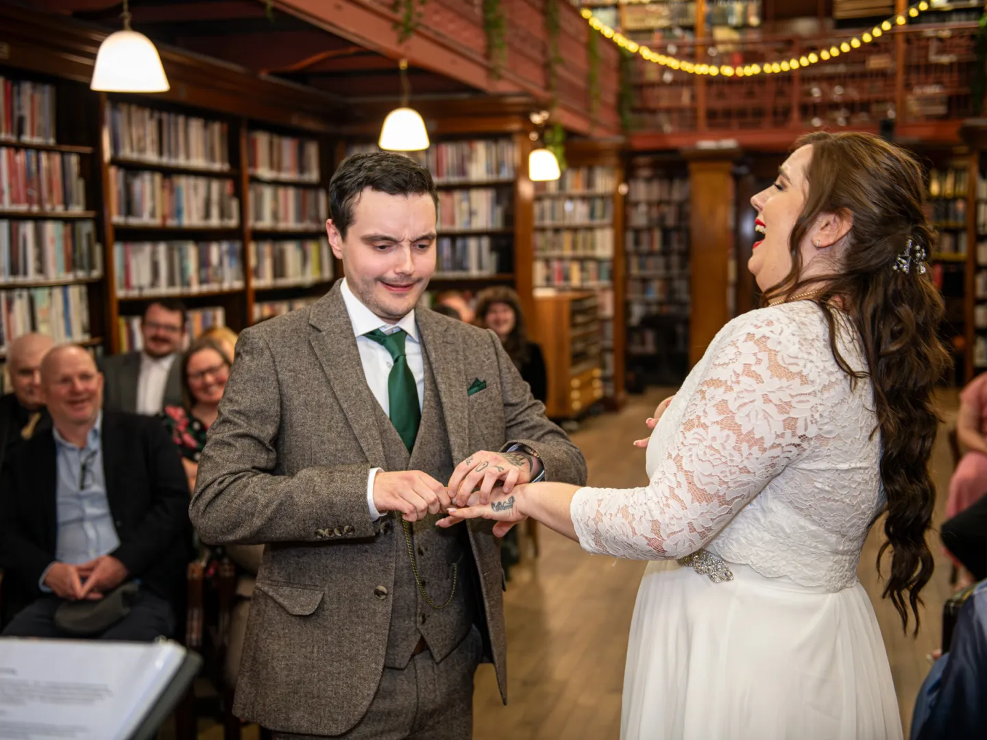 A funny face being pulled by the groom while placing a ring on the brides finger