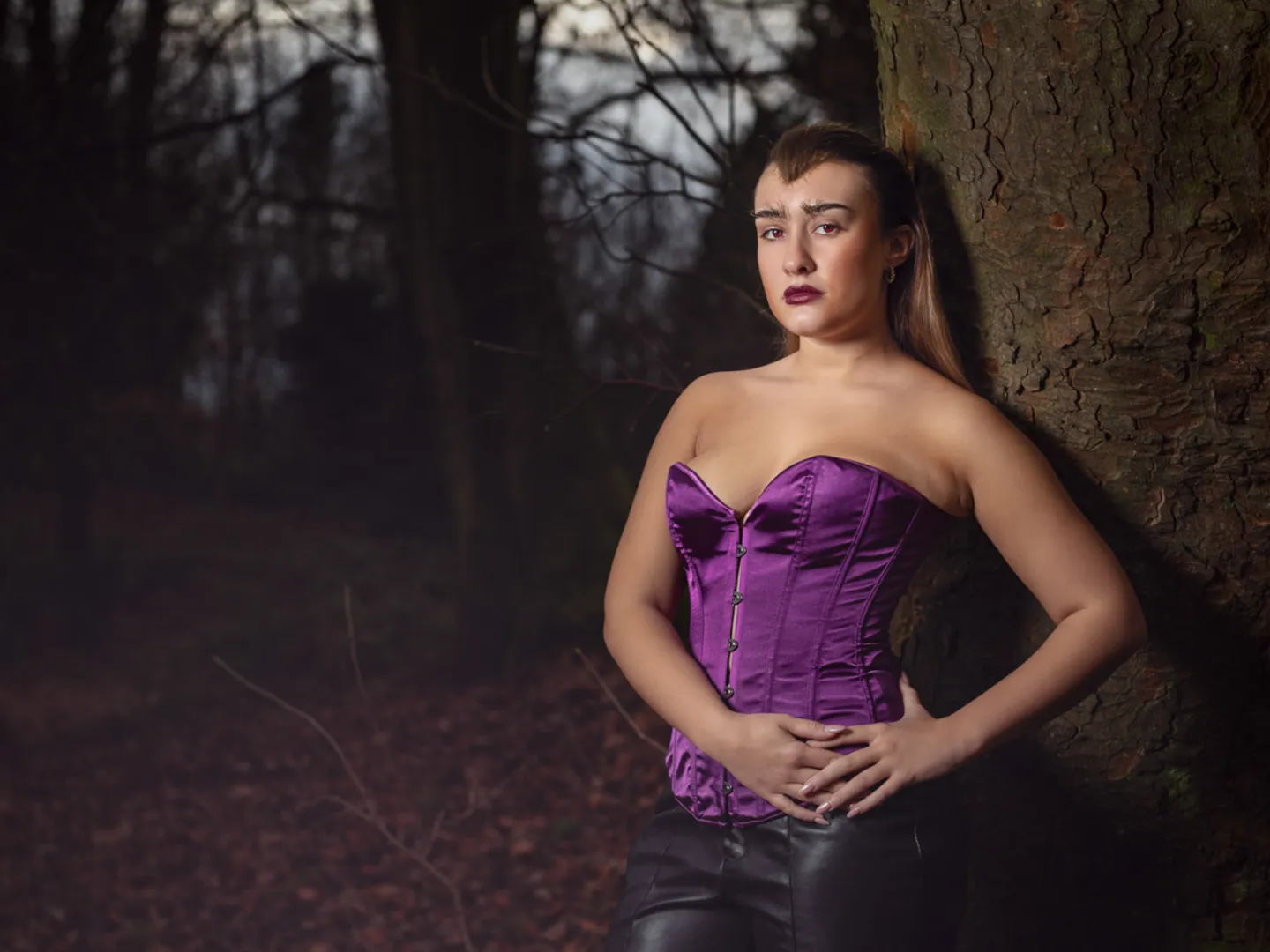 Woman standing against a tree with a vampire look