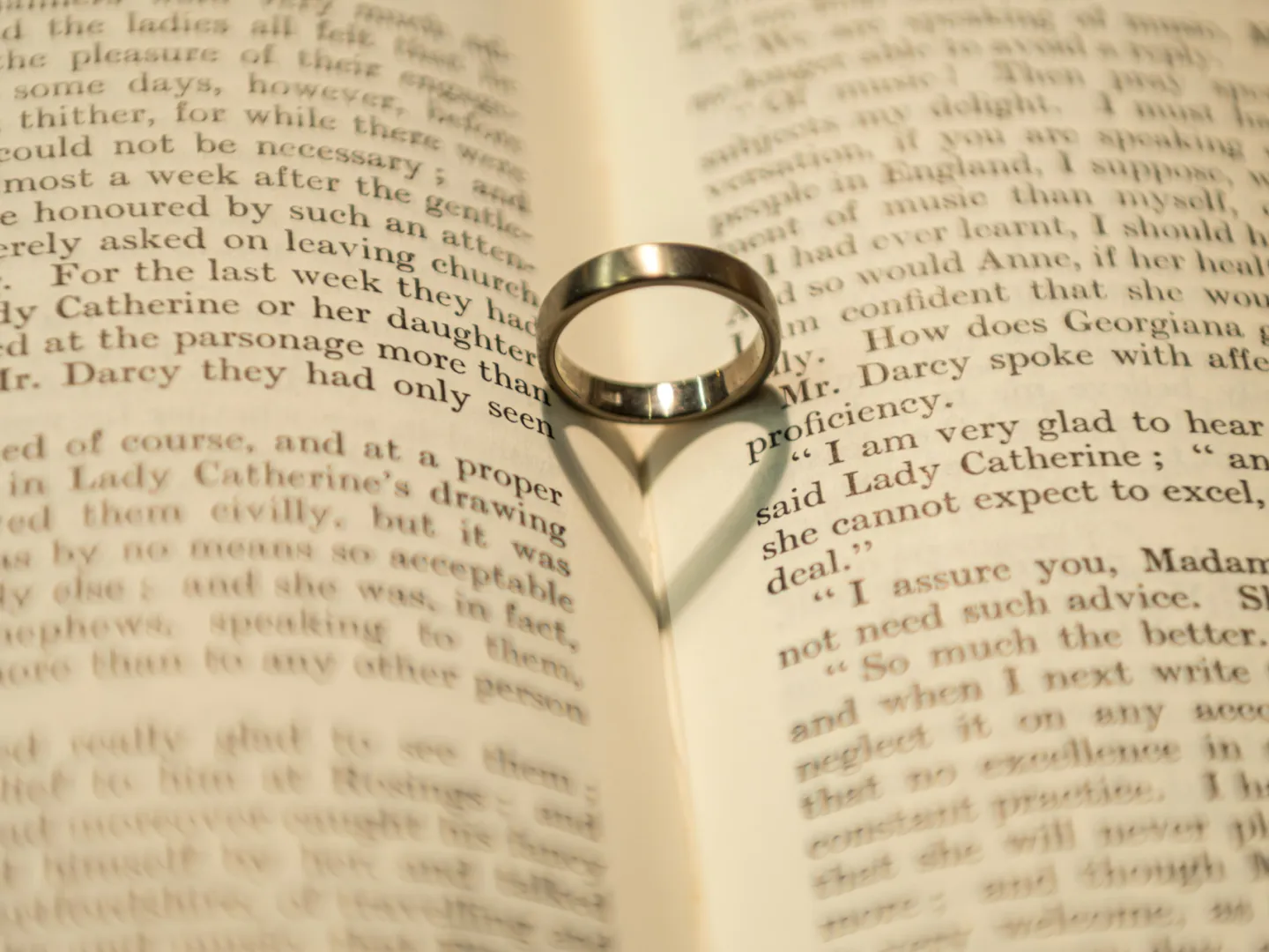 Wedding ring in the center of a book with a shadow of a heart