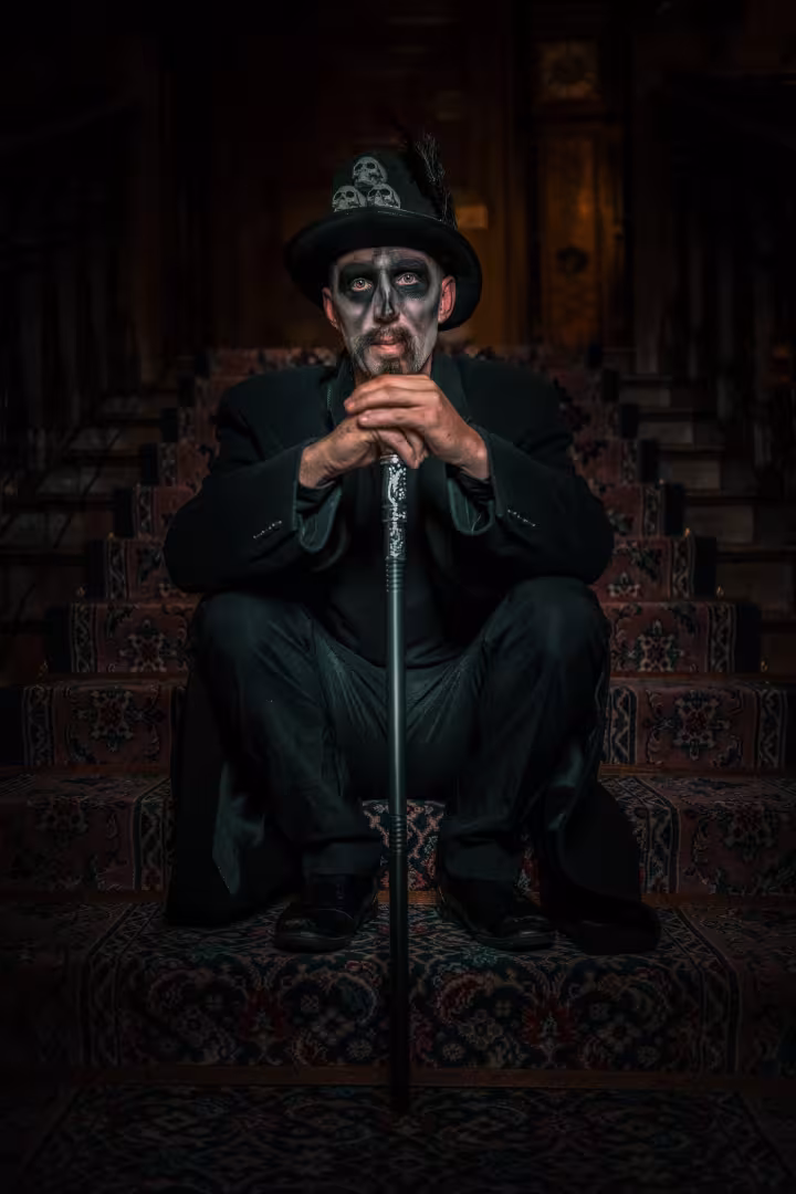 Voodoo man sitting on stairs with cane